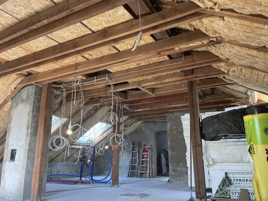 Offener Dachstuhl mit Holzbalken und Dämmung vor dem Ausbau